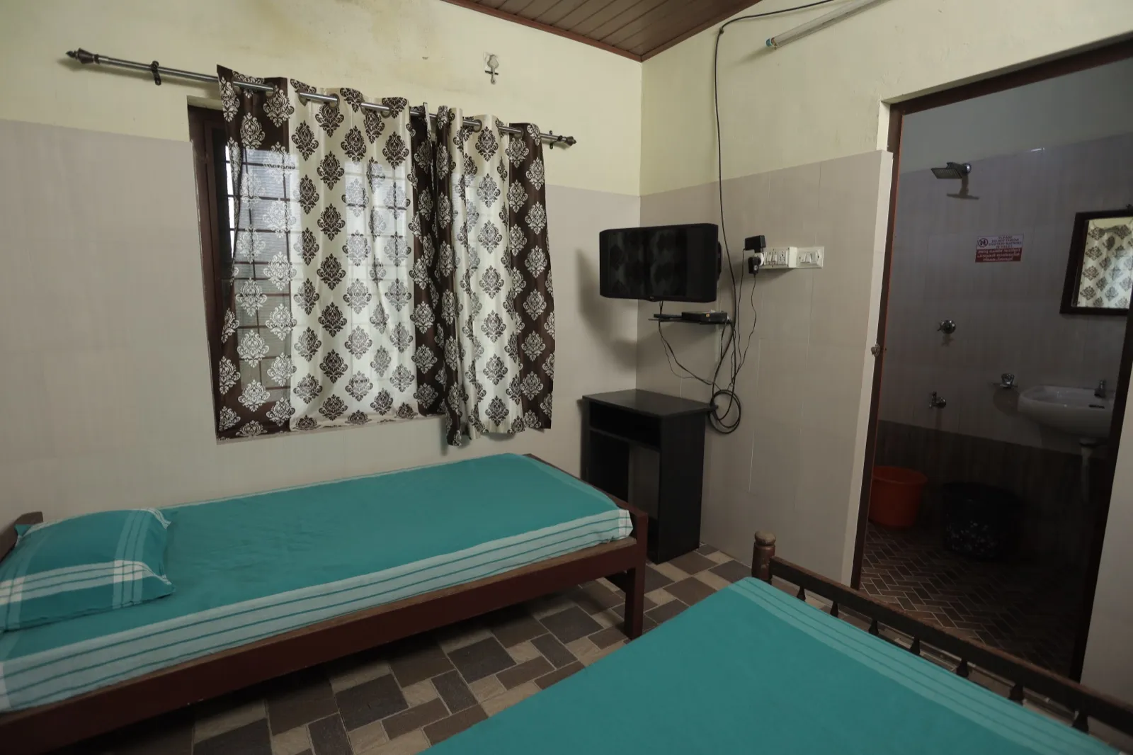 Air-conditioned patient room with TV and attached bathroom at Agasthya Ayurvedic Hospital